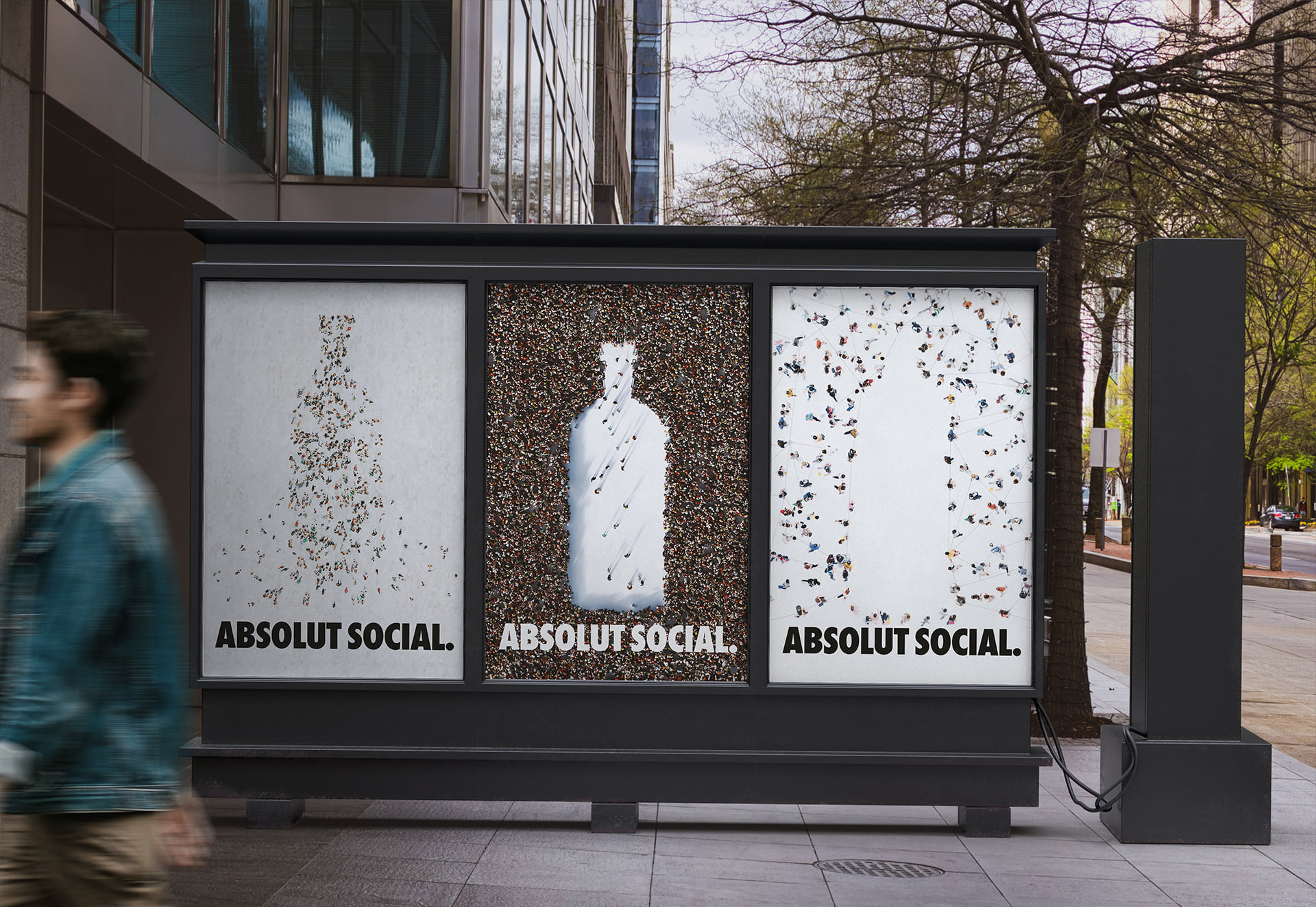 A street display with three backlit panels showing the gathering, clearing and network ads side by side, and a passerby walking past in the foreground.