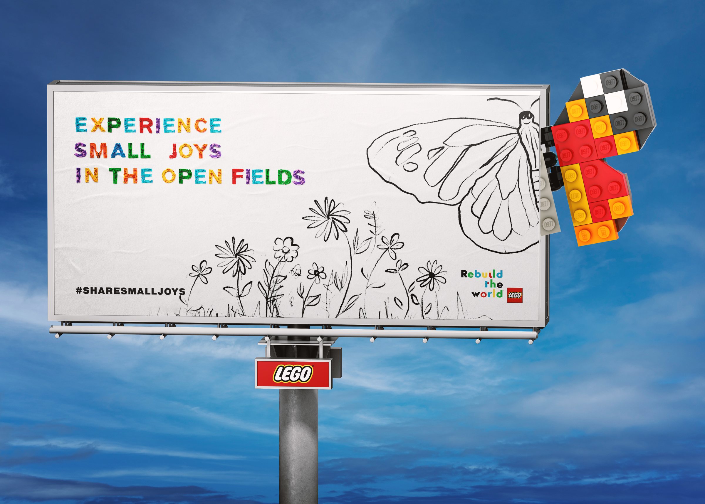 A billboard against a blue sky with pencil-drawn wildflowers and half a butterfly. The other half, built from red, orange, yellow and gray LEGO bricks, flies out past the right edge. The headline reads Experience small joys in the open fields.