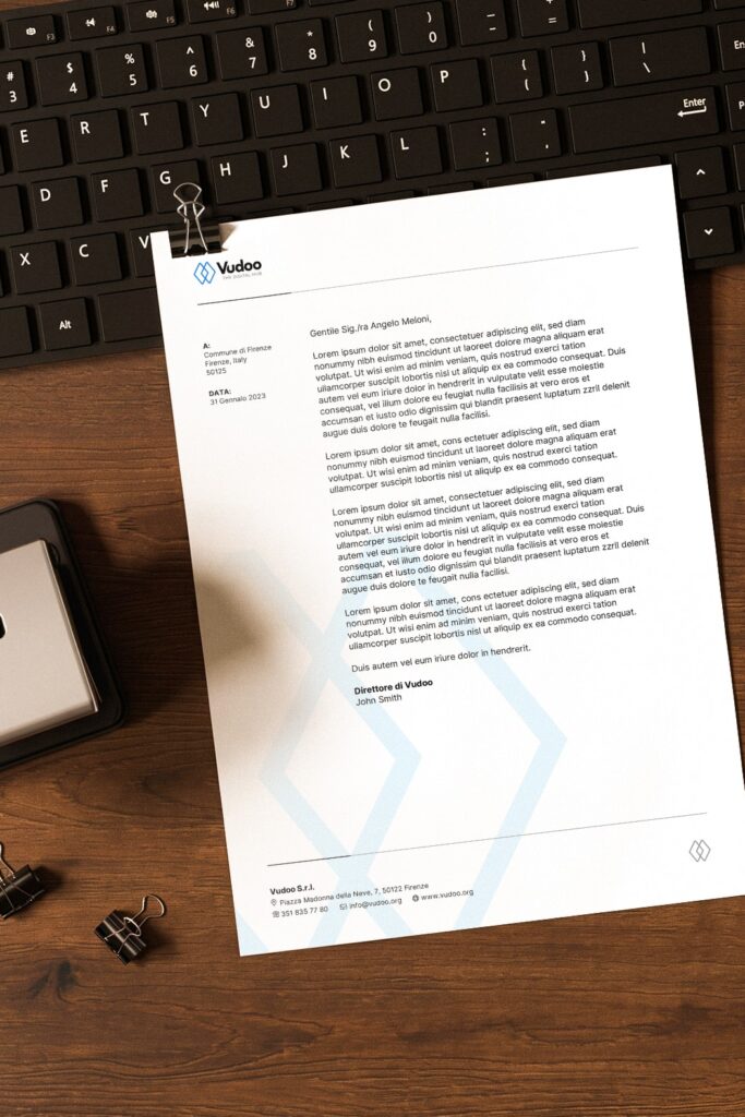 A Vudoo letterhead on a wooden desk beside a keyboard, with the logo at the top and a faint diamond pattern behind the text.